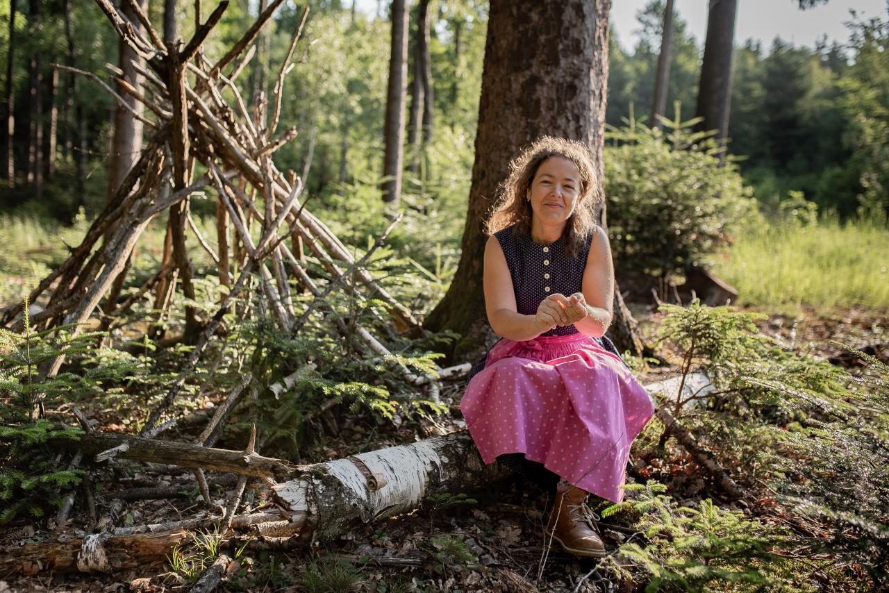 Erzählerin Sabina Haslinger, Familien-Märchenwanderung der Pfarrbücherei Vöcklabruck. Sabina Haslinger sitzt hier im Wald vor einem Baum